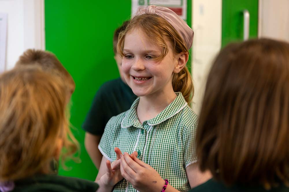 Oracy Centre of Excellence, Cornwall, Lostwithiel Primary A girl communicating with friends at Lostwithiel Primary